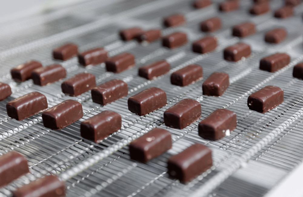 Chocolate sweets candy on industry conveyor. Modern production line of food factory Coating Tynic Automation